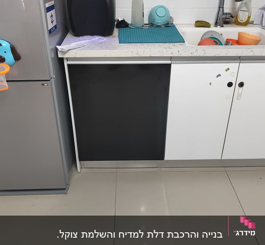 מטבח עם כיור, כלים, מקרר וארונות לבנים